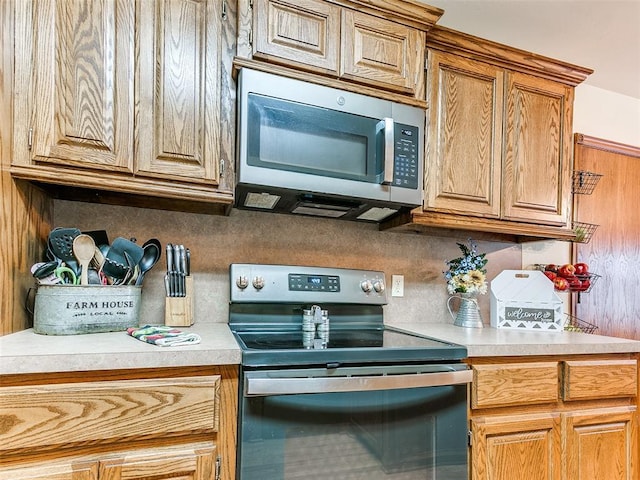 409 NW Jefferson Ave, Piedmont, OK 73078 - kitchen featuring appliances with stainless steel finishes, light countertops, and brown cabinets