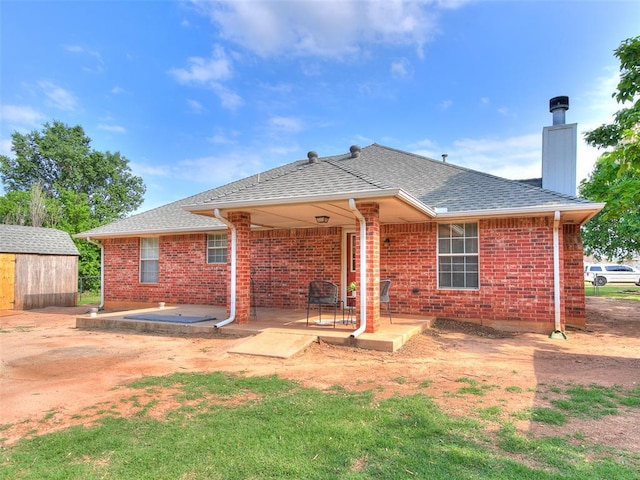409 NW Jefferson Ave, Piedmont, OK 73078 - rear view of property with a chimney, brick siding, a shingled roof, and a patio