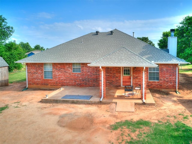 409 NW Jefferson Ave, Piedmont, OK 73078 - rear view of house with a chimney, a patio, a shingled roof, and brick siding