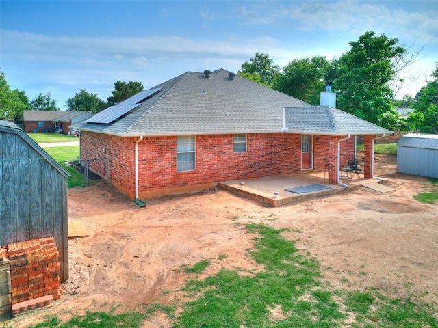 409 NW Jefferson Ave, Piedmont, OK 73078 - rear view of property with a chimney, brick siding, a shingled roof, and solar panels