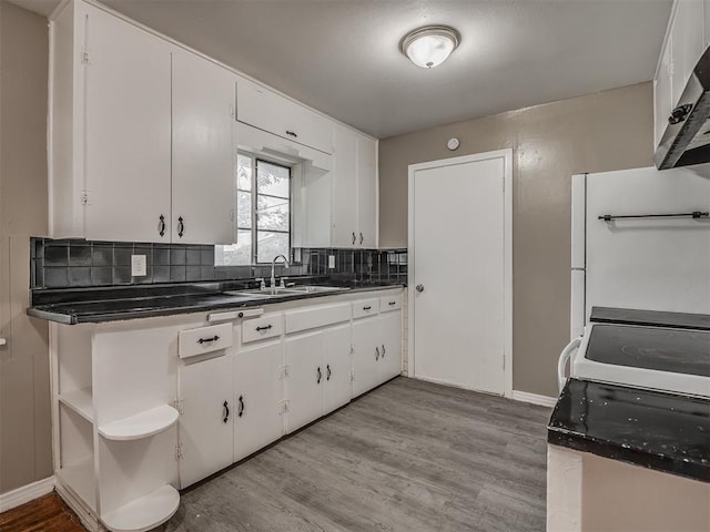 4109 N Sterling Ave, Oklahoma City, OK 73122 - kitchen featuring dark countertops, range hood, backsplash, light wood finished floors, and white cabinetry