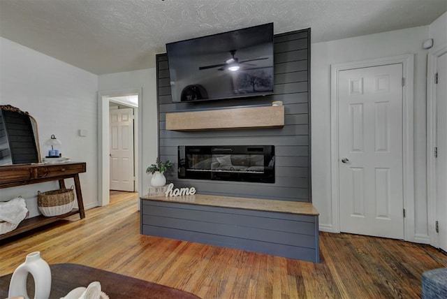 2805 SW 54th Pl, Oklahoma City, OK 73119 - living area with a large fireplace, wood finished floors, a ceiling fan, a textured ceiling, and baseboards