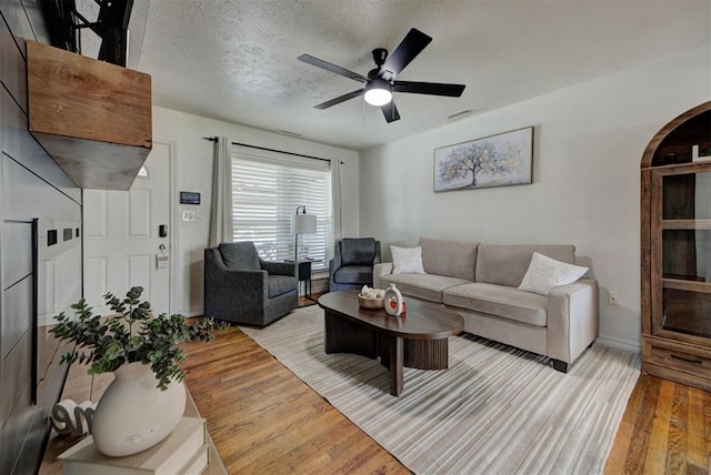 2805 SW 54th Pl, Oklahoma City, OK 73119 - living room featuring arched walkways, wood finished floors, ceiling fan, baseboards, and a textured ceiling