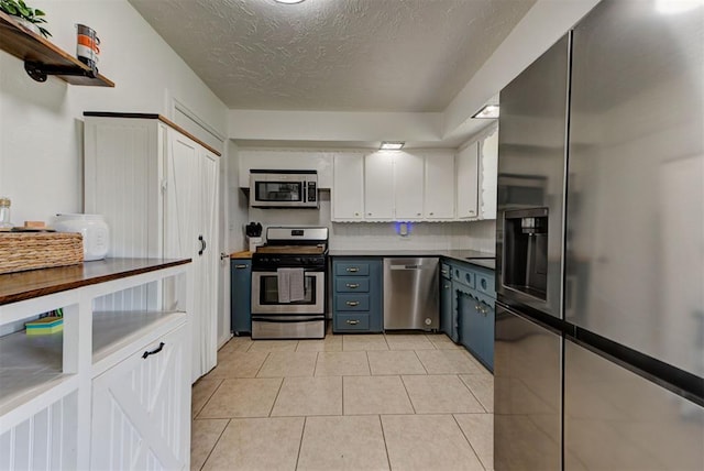 2805 SW 54th Pl, Oklahoma City, OK 73119 - kitchen with stainless steel appliances, white cabinetry, a textured ceiling, dark countertops, and blue cabinets