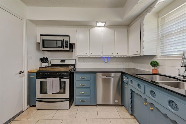 2805 SW 54th Pl, Oklahoma City, OK 73119 - kitchen with stainless steel appliances, a sink, white cabinets, dark countertops, and light tile patterned floors