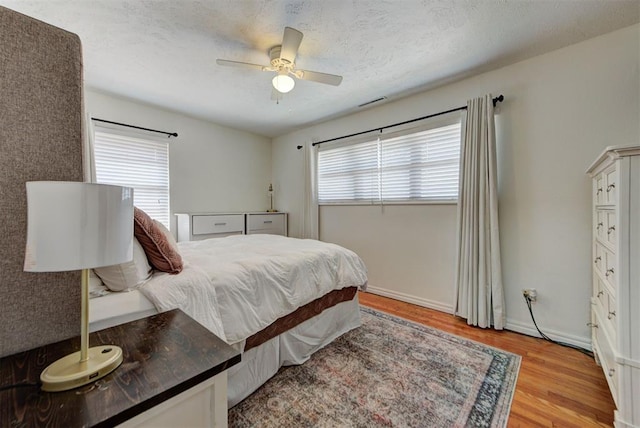 2805 SW 54th Pl, Oklahoma City, OK 73119 - bedroom featuring light wood-style flooring, a textured ceiling, a ceiling fan, and baseboards