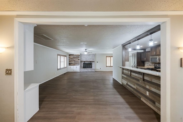 325 S Pine St, Crescent, OK 73028 - unfurnished living room with dark wood finished floors, a ceiling fan, plenty of natural light, a large fireplace, and a textured ceiling