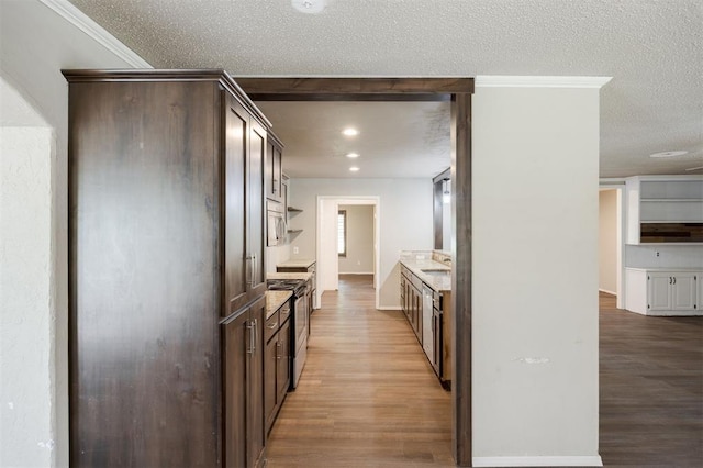 325 S Pine St, Crescent, OK 73028 - kitchen featuring stainless steel range with electric stovetop, a sink, dark brown cabinetry, light wood-style flooring, and a textured ceiling