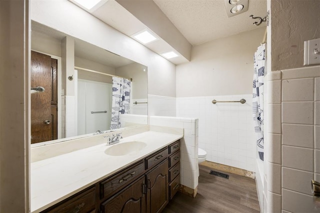 325 S Pine St, Crescent, OK 73028 - full bath with wood finished floors, tile walls, a wainscoted wall, vanity, and toilet
