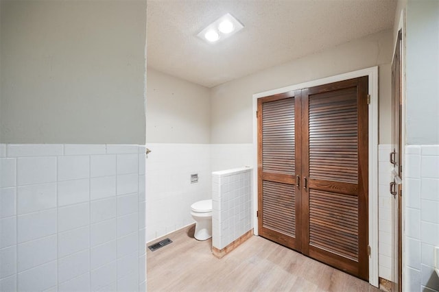 325 S Pine St, Crescent, OK 73028 - bathroom featuring tile walls, wainscoting, toilet, and wood finished floors
