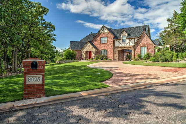 8025 Redbud Canyon Trl, Edmond, OK 73034 - tudor house featuring decorative driveway, a front lawn, brick siding, and stone siding