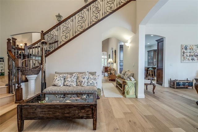 8025 Redbud Canyon Trl, Edmond, OK 73034 - living room featuring arched walkways, wood finished floors, baseboards, stairs, and a high ceiling