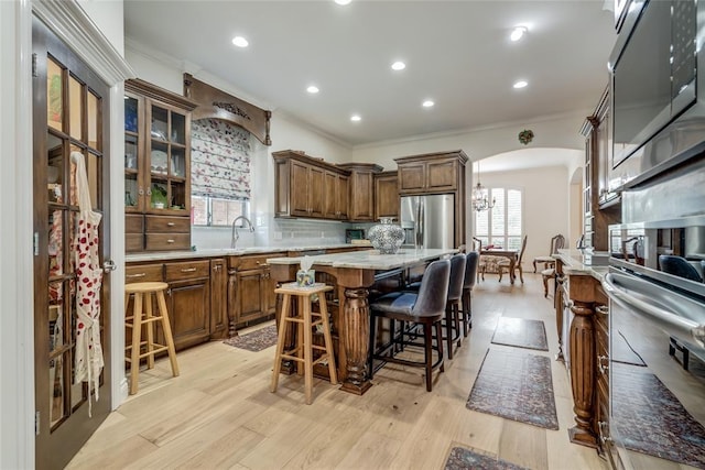 8025 Redbud Canyon Trl, Edmond, OK 73034 - kitchen featuring ornamental molding, arched walkways, a kitchen island, appliances with stainless steel finishes, and decorative backsplash