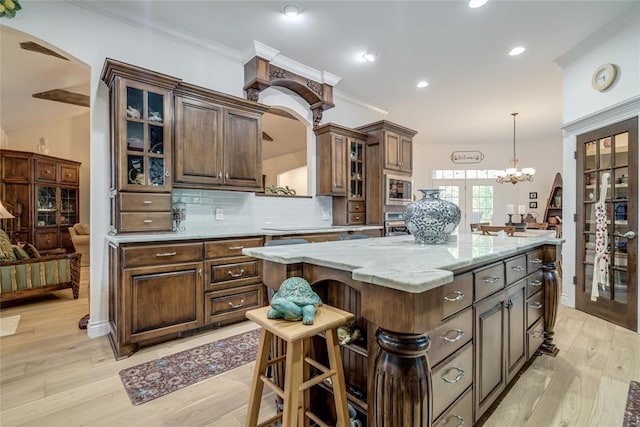 8025 Redbud Canyon Trl, Edmond, OK 73034 - kitchen with arched walkways, appliances with stainless steel finishes, decorative backsplash, crown molding, and light wood-style flooring