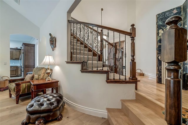 8025 Redbud Canyon Trl, Edmond, OK 73034 - stairway featuring baseboards, wood finished floors, arched walkways, and high vaulted ceiling