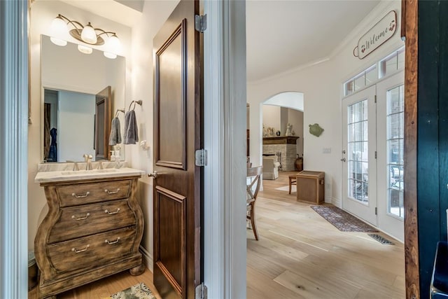 8025 Redbud Canyon Trl, Edmond, OK 73034 - bathroom featuring a stone fireplace, wood finished floors, vanity, ornamental molding, and french doors