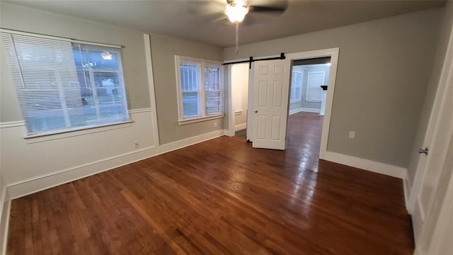 929 NE 17th St, Oklahoma City, OK 73105 - unfurnished bedroom with a barn door, wood finished floors, baseboards, and ceiling fan