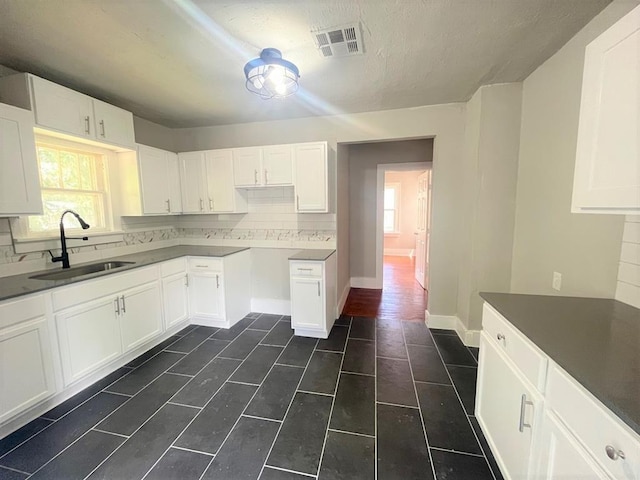 929 NE 17th St, Oklahoma City, OK 73105 - kitchen with a sink, tasteful backsplash, white cabinets, dark tile patterned flooring, and baseboards