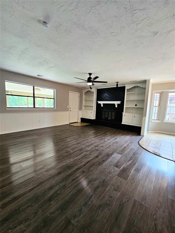 6013 Greenview Dr, Oklahoma City, OK 73135 - unfurnished living room featuring a fireplace, ceiling fan, dark wood-style floors, and a textured ceiling