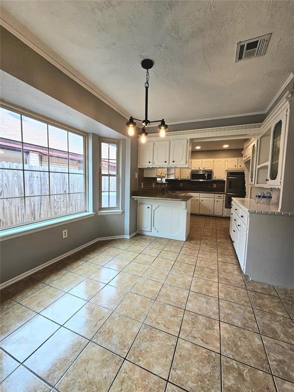 6013 Greenview Dr, Oklahoma City, OK 73135 - kitchen featuring crown molding, a peninsula, light tile patterned floors, baseboards, and a textured ceiling