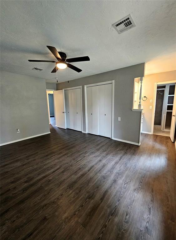 6013 Greenview Dr, Oklahoma City, OK 73135 - unfurnished bedroom with dark wood finished floors, baseboards, a textured ceiling, two closets, and a ceiling fan