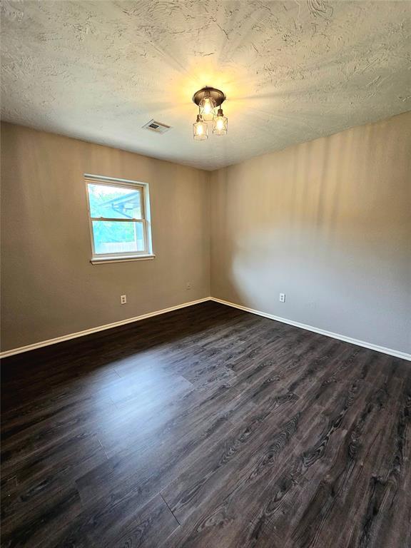 6013 Greenview Dr, Oklahoma City, OK 73135 - empty room featuring dark wood-style flooring, baseboards, and a textured ceiling