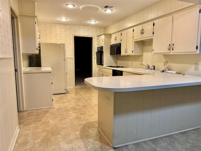 1618 NW 24th St, Lawton, OK 73505 - kitchen featuring a sink, black appliances, wallpapered walls, a peninsula, and light countertops