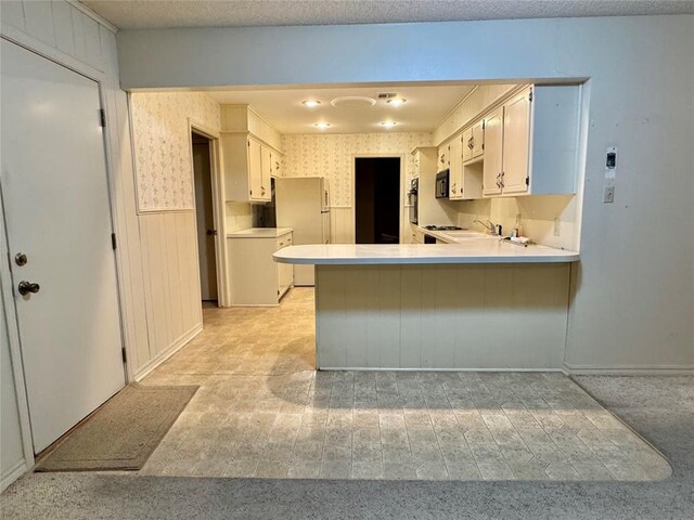 1618 NW 24th St, Lawton, OK 73505 - kitchen featuring black appliances, a peninsula, light countertops, a wainscoted wall, and a sink