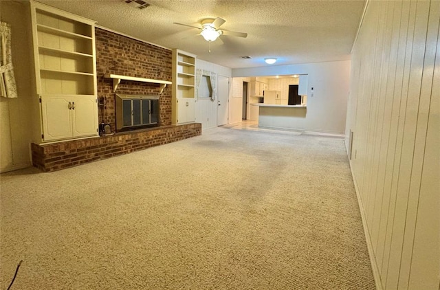 1618 NW 24th St, Lawton, OK 73505 - unfurnished living room featuring a ceiling fan, a textured ceiling, light carpet, wooden walls, and a brick fireplace