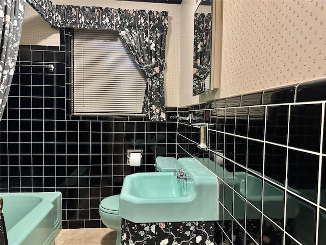1618 NW 24th St, Lawton, OK 73505 - bathroom with wallpapered walls, toilet, tile walls, a wainscoted wall, and a bath