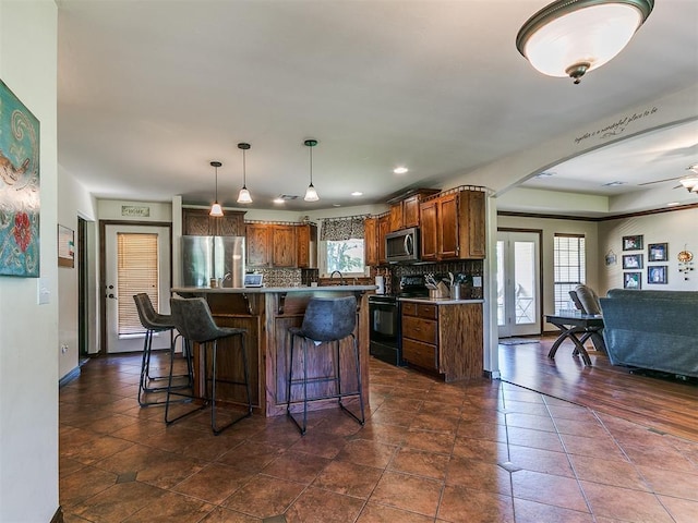 5509 Old Town St, Newalla, OK 74857 - kitchen with appliances with stainless steel finishes, arched walkways, backsplash, a breakfast bar, and recessed lighting