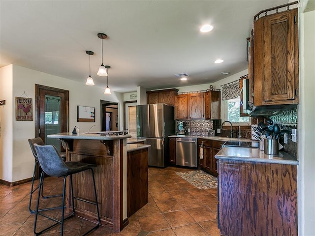 5509 Old Town St, Newalla, OK 74857 - kitchen featuring stainless steel appliances, a sink, a breakfast bar area, tasteful backsplash, and pendant lighting
