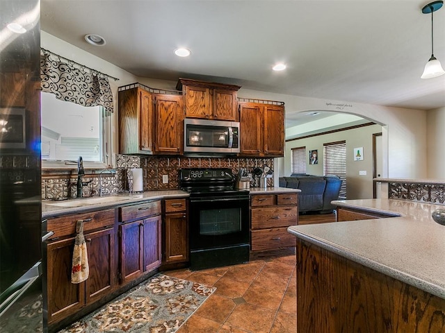 5509 Old Town St, Newalla, OK 74857 - kitchen with black range with electric cooktop, stainless steel microwave, a sink, arched walkways, and decorative backsplash