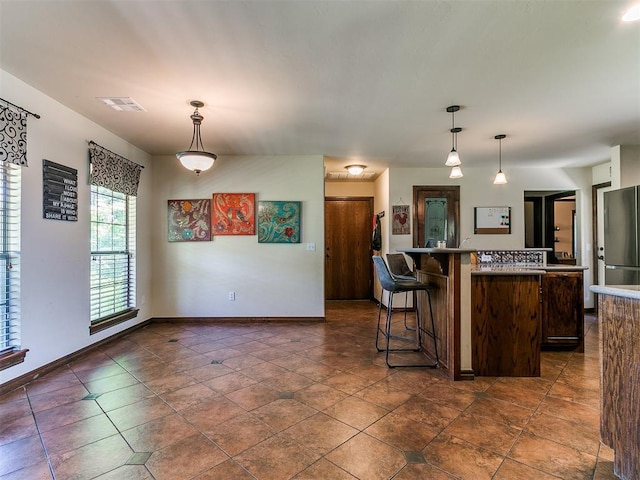 5509 Old Town St, Newalla, OK 74857 - kitchen featuring freestanding refrigerator, a kitchen breakfast bar, decorative light fixtures, dark brown cabinetry, and a kitchen island