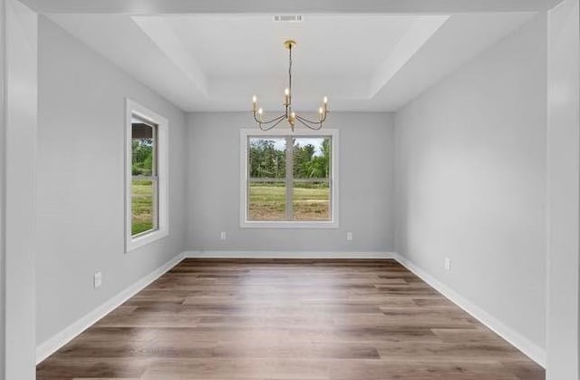 3155 E Fair St, Idabel, OK 74745 - spare room featuring a chandelier, plenty of natural light, a raised ceiling, and wood finished floors
