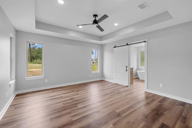 3155 E Fair St, Idabel, OK 74745 - unfurnished bedroom with a tray ceiling, a barn door, wood finished floors, recessed lighting, and baseboards
