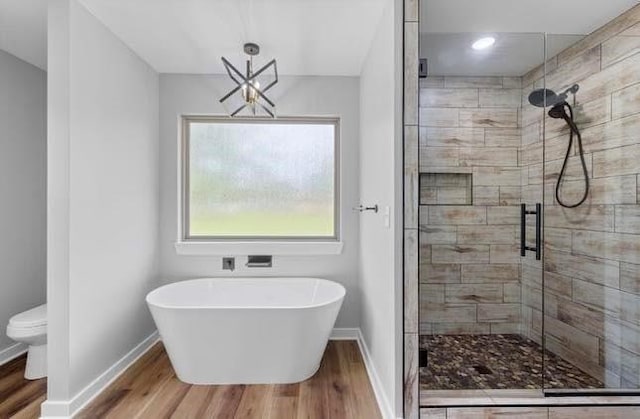 3155 E Fair St, Idabel, OK 74745 - full bathroom featuring wood finished floors, a shower stall, toilet, baseboards, and a freestanding tub