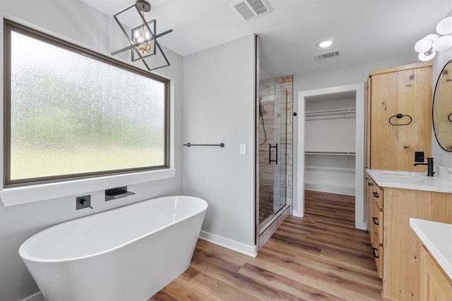 3155 E Fair St, Idabel, OK 74745 - bathroom featuring vanity, a stall shower, a soaking tub, wood finished floors, and a walk in closet