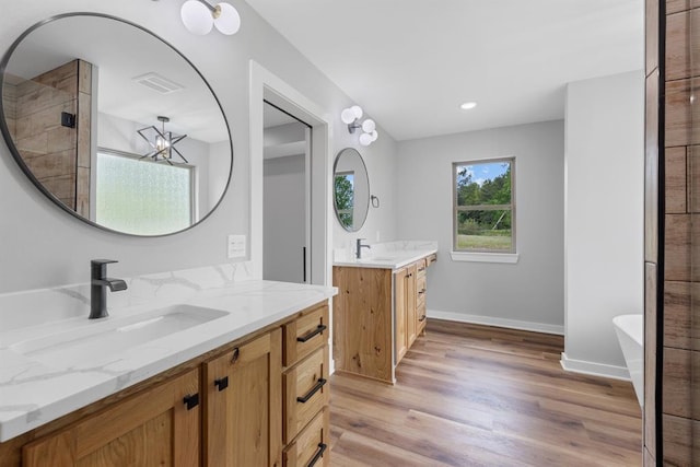 3155 E Fair St, Idabel, OK 74745 - full bathroom with two vanities, wood finished floors, a soaking tub, and baseboards