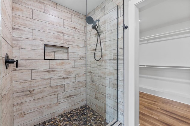 3155 E Fair St, Idabel, OK 74745 - bathroom featuring a tile shower, a walk in closet, and wood finished floors