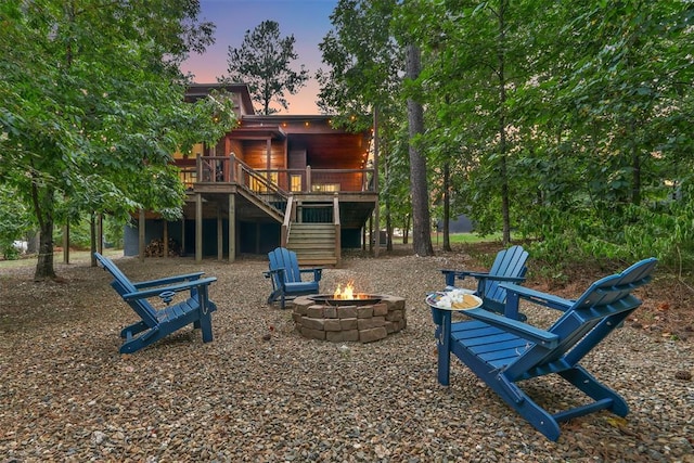 168 Eagle Mountain Trl, Broken Bow, OK 74728 - playground at dusk featuring an outdoor fire pit, stairway, and a deck
