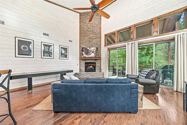 168 Eagle Mountain Trl, Broken Bow, OK 74728 - living room featuring a towering ceiling, healthy amount of natural light, a ceiling fan, wooden walls, and a stone fireplace