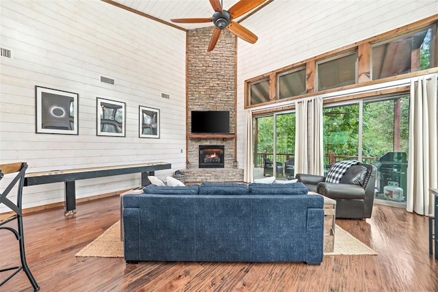 168 Eagle Mountain Trl, Broken Bow, OK 74728 - living area featuring a high ceiling, healthy amount of natural light, a ceiling fan, wooden walls, and a stone fireplace