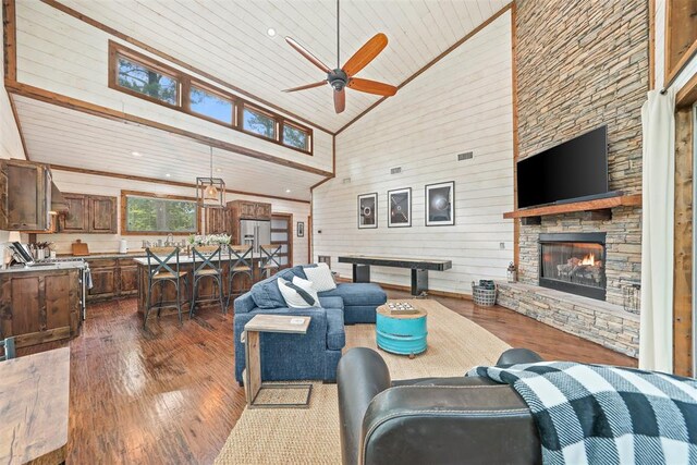 168 Eagle Mountain Trl, Broken Bow, OK 74728 - living area with dark wood-style flooring, high vaulted ceiling, ceiling fan, wood walls, and a stone fireplace