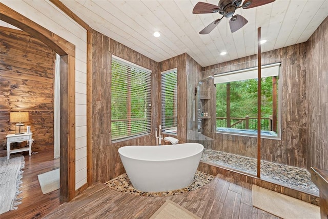 168 Eagle Mountain Trl, Broken Bow, OK 74728 - full bathroom featuring walk in shower, a freestanding bath, wood walls, hardwood / wood-style flooring, and a ceiling fan