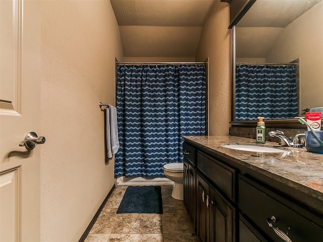 17016 Barcelona Dr, Oklahoma City, OK 73170 - bathroom featuring vanity, toilet, vaulted ceiling, a textured wall, and stone finish floors