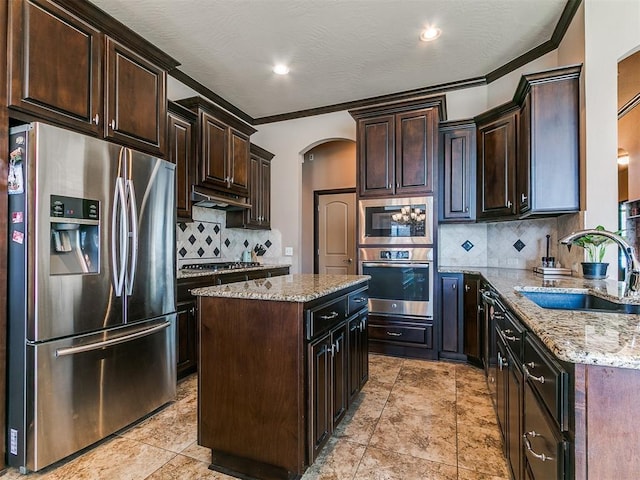 17016 Barcelona Dr, Oklahoma City, OK 73170 - kitchen with appliances with stainless steel finishes, a sink, arched walkways, light stone countertops, and decorative backsplash