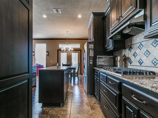 17016 Barcelona Dr, Oklahoma City, OK 73170 - kitchen featuring appliances with stainless steel finishes, a chandelier, ornamental molding, under cabinet range hood, and tasteful backsplash