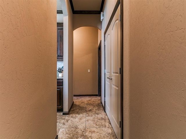 17016 Barcelona Dr, Oklahoma City, OK 73170 - corridor with a textured wall, arched walkways, ornamental molding, and light stone finish floors