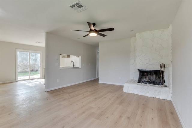 812 NW 113th St, Oklahoma City, OK 73114 - unfurnished living room featuring a ceiling fan, light wood-style flooring, a stone fireplace, and baseboards